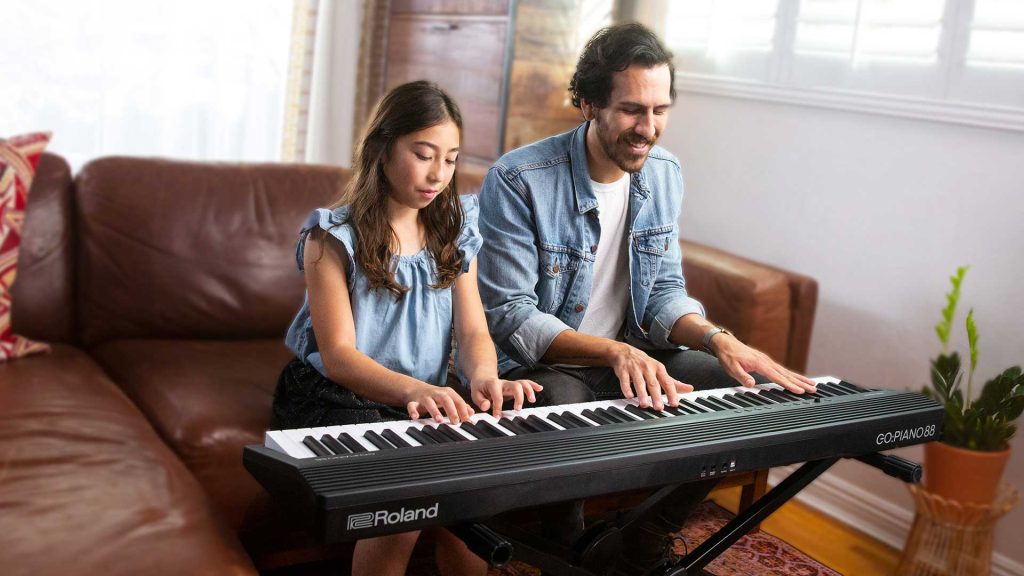 Cild and Parent playing a Roland GO:PIANO